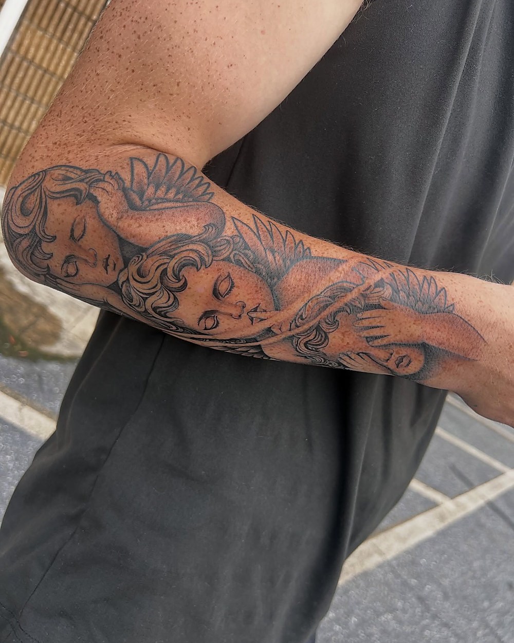 Three cherubs down a forearm, by Kevin Lewis