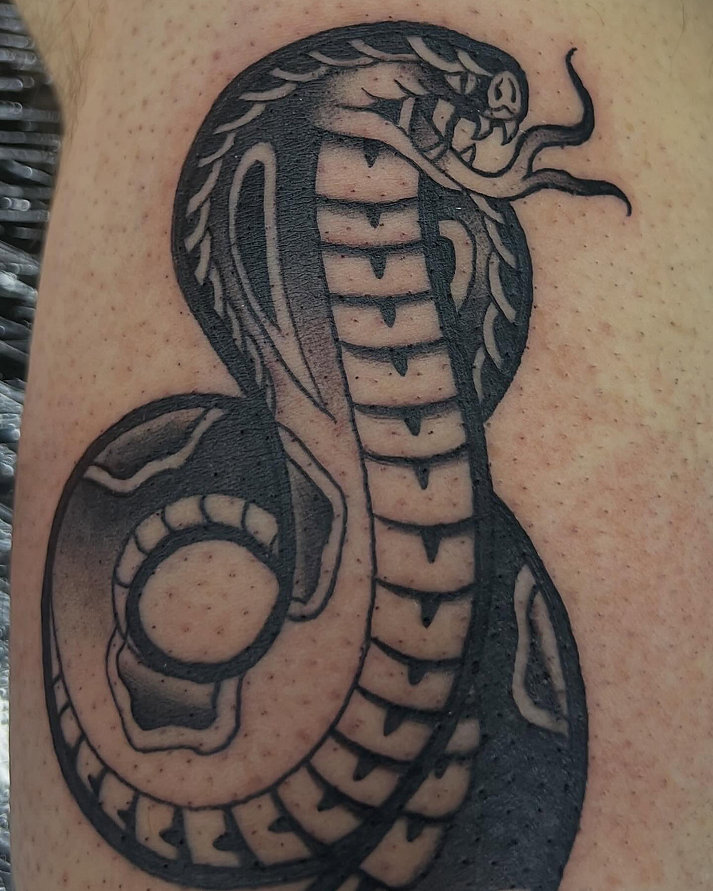 Traditional cobra on a forearm, by Kevin Lewis