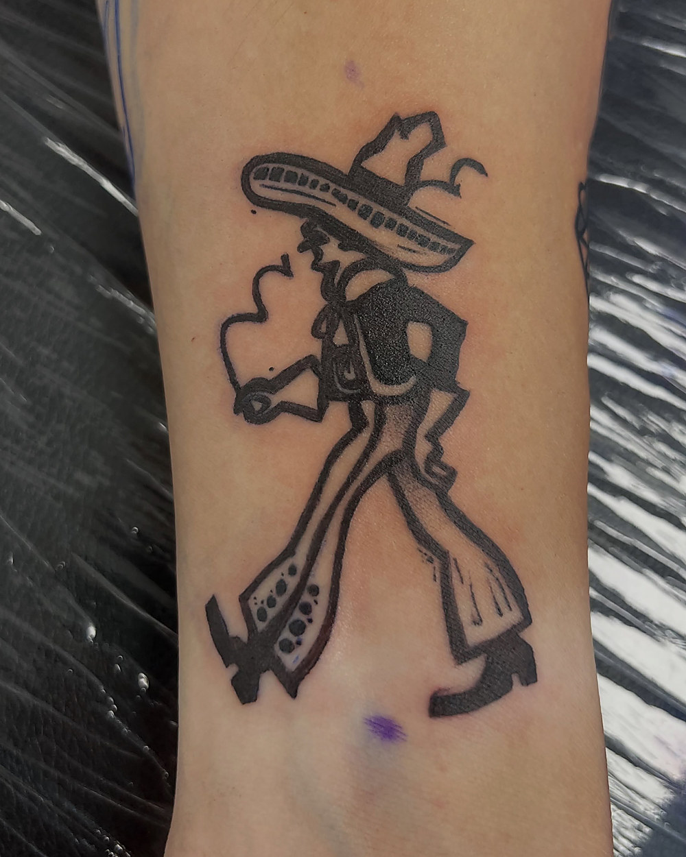 A cartoon figure in a sombrero, linework on a forearm, by Kevin Lewis