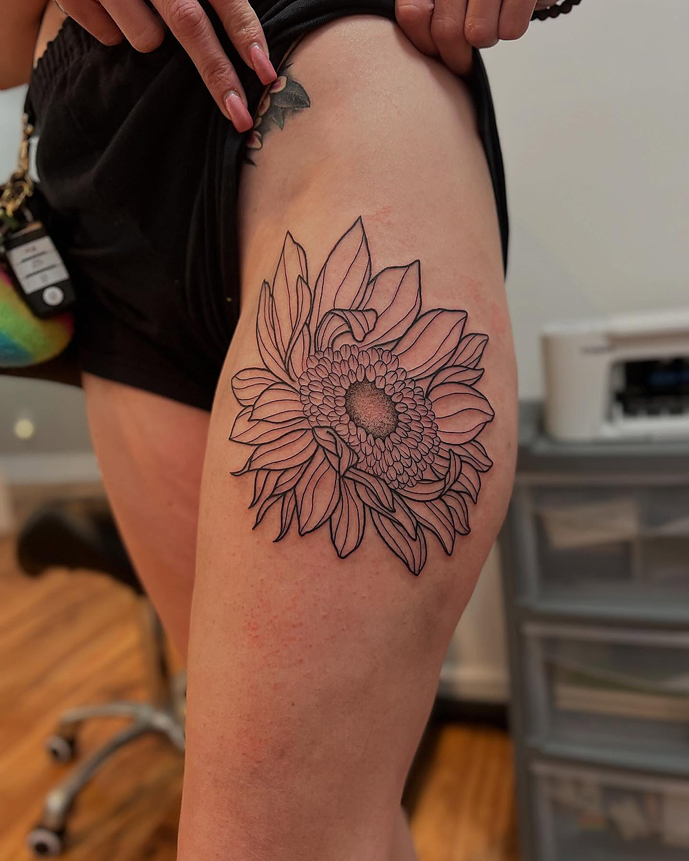 Fine line sunflower on a thigh, by Kevin Lewis