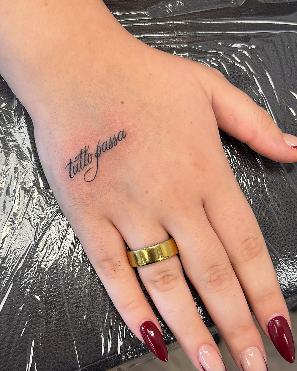 Fine line script across the back of a hand, by Miah