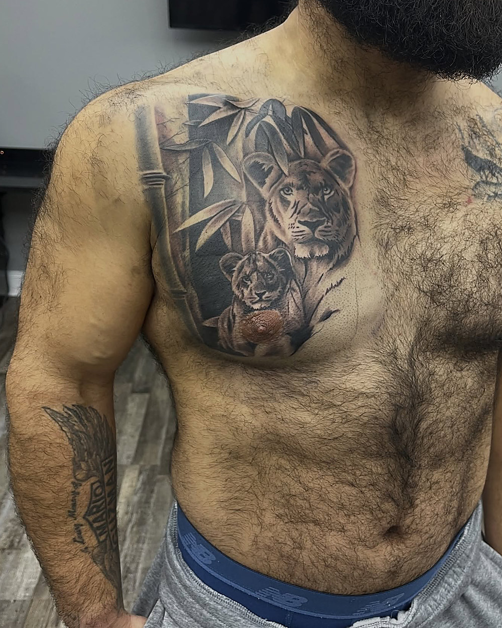 Lion and cub chest piece in black and grey, by Owen Lewis