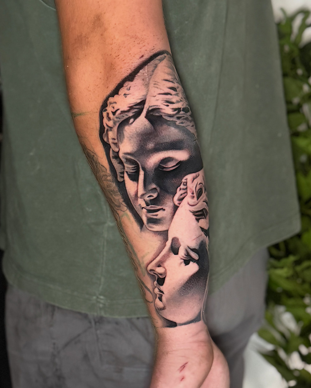Classical statue in black and grey on a forearm, by Owen Lewis