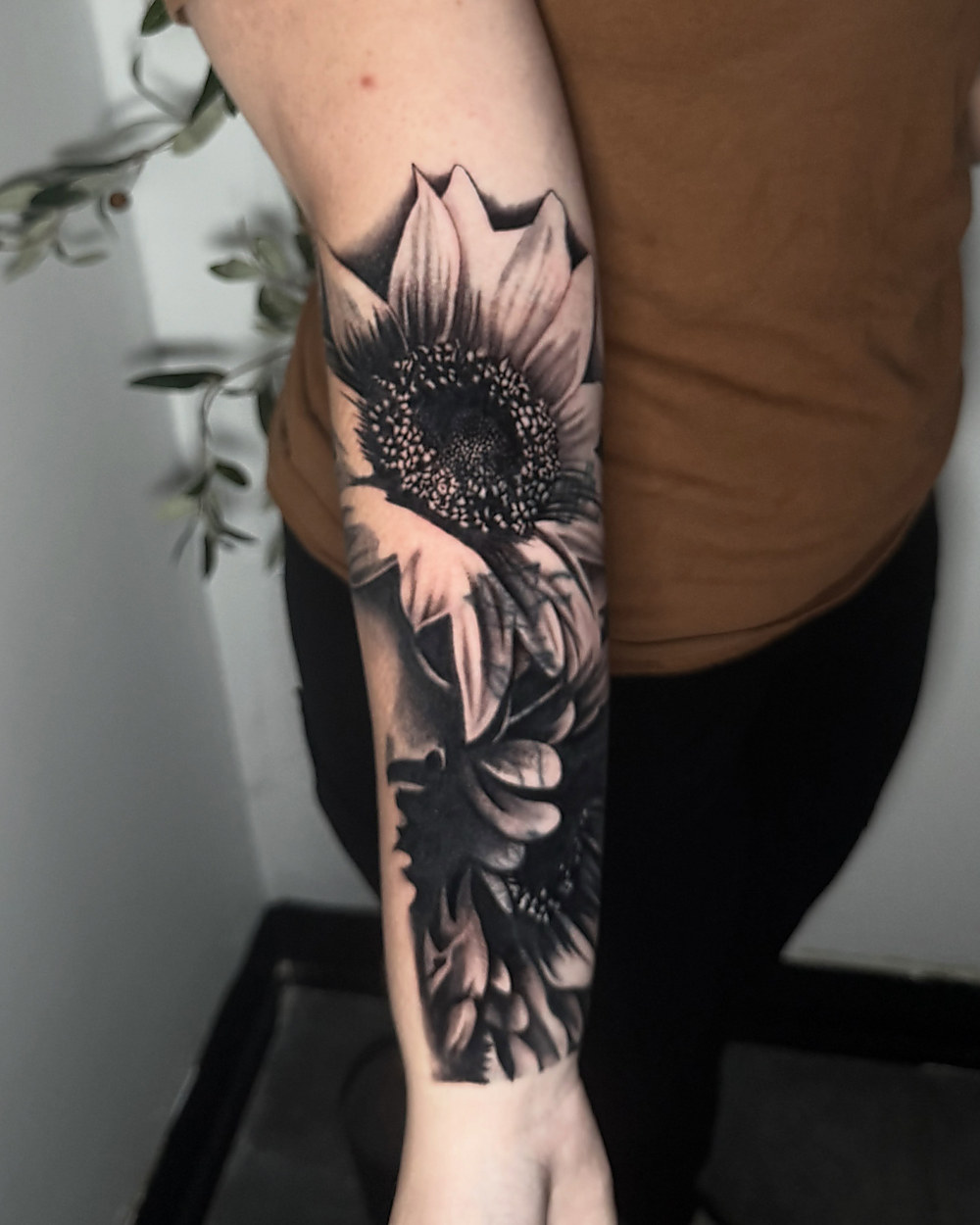 Black and grey sunflower on a forearm, by Owen Lewis