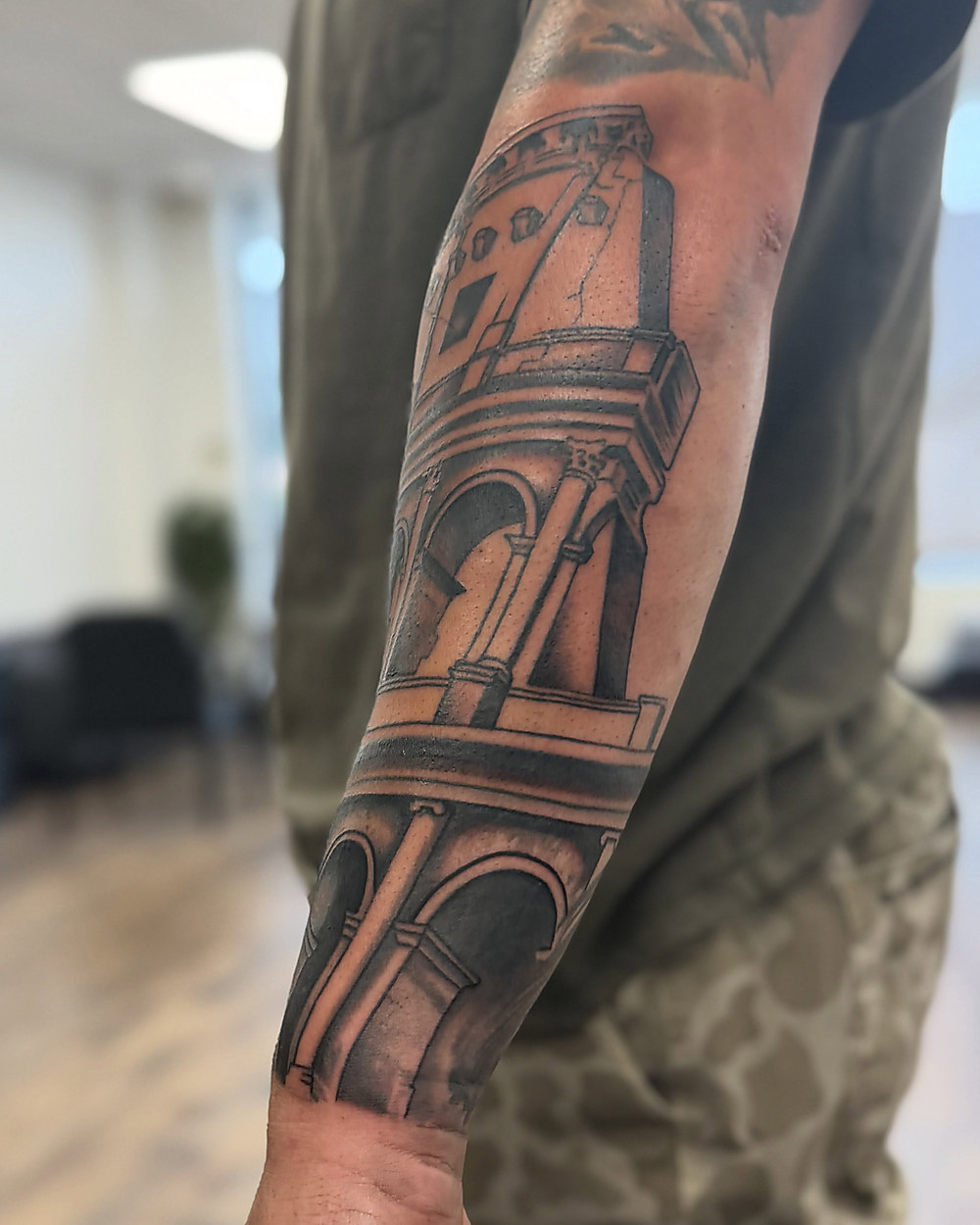 Stone tower in black and grey on a forearm, by Owen Lewis